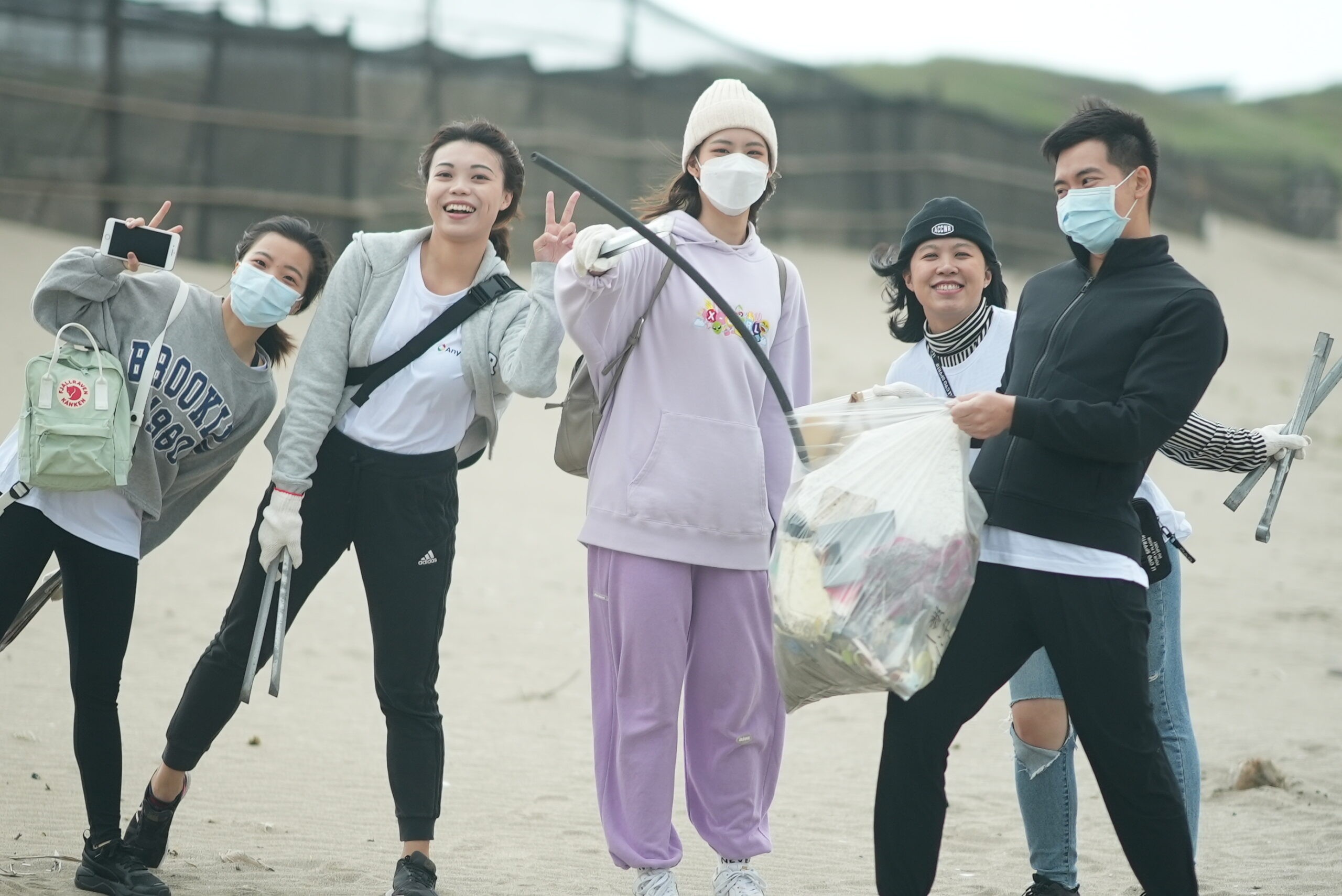 Các thành viên đội AnyMind Group chụp ảnh lưu niệm sau khi thu gom rác trên bãi biển, thể hiện niềm vui và tinh thần đồng đội khi &quot;we can clean the beach together&quot;